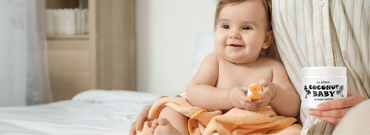 Mother holding a jar of Coconut Baby oil next to her smiling baby (desktop)