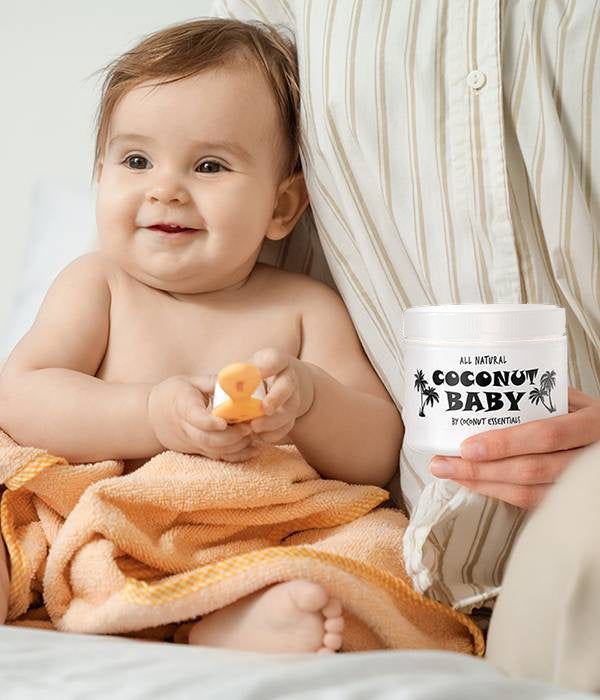 Mother holding a jar of Coconut Baby oil next to her smiling baby (mobile)