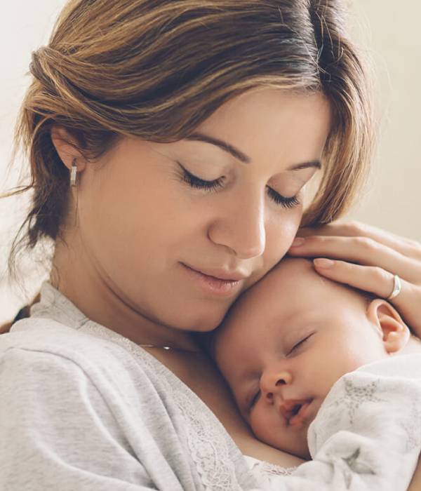 Photo of a mother holding a sleeping baby to her chest.