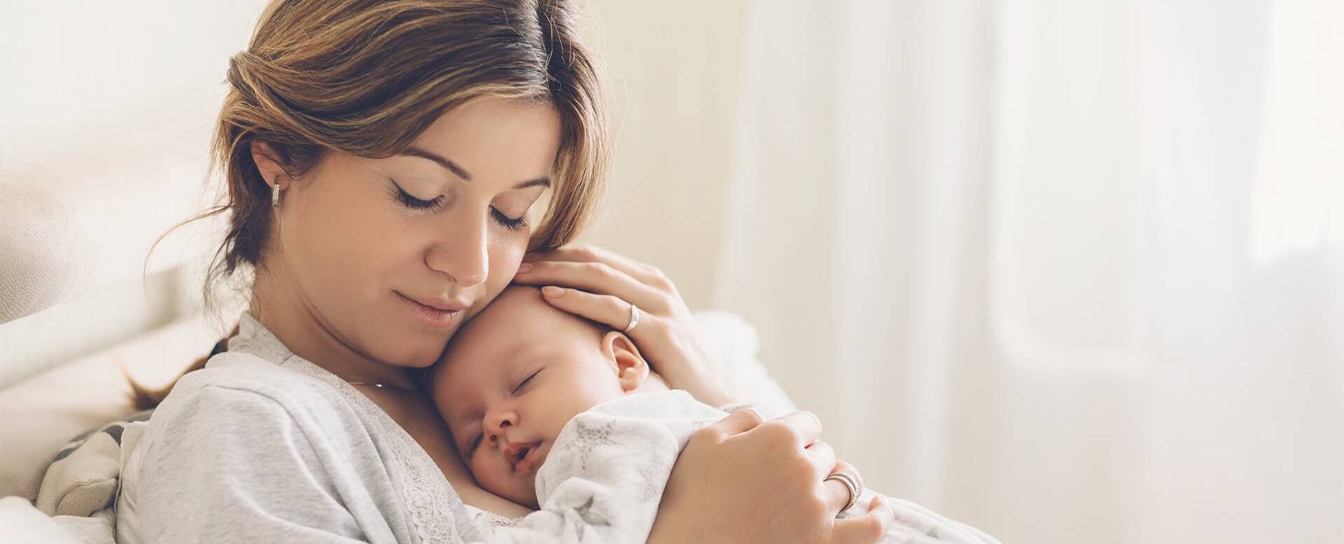 Photo of a mother holding a sleeping baby to her chest.